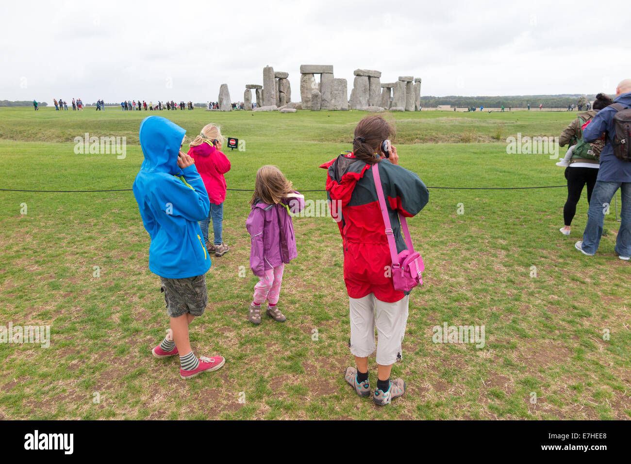 I visitatori di Stonehenge: Stone Henge con turisti turistico / famiglia / mamma madre e bambini / bambini ascolto di audio guida. Regno Unito Foto Stock
