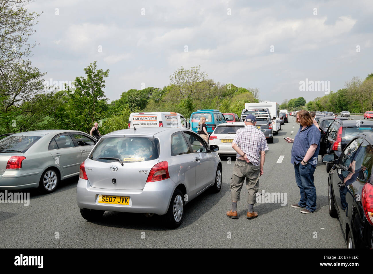 Persone che si trovano sulla carreggiata fuori dai veicoli fermi in un ingorgo stradale sull'autostrada M6 a causa di incidenti che causano un lungo ritardo. Inghilterra Regno Unito Foto Stock