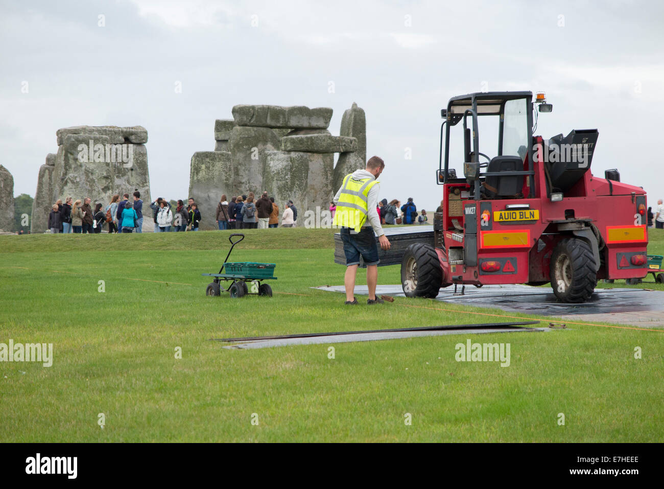 Lavoratore lavora presso la posa di fogli protettivi a Stonehenge / Pietra sito Henge con turisti / tourist in background. Regno Unito. Foto Stock
