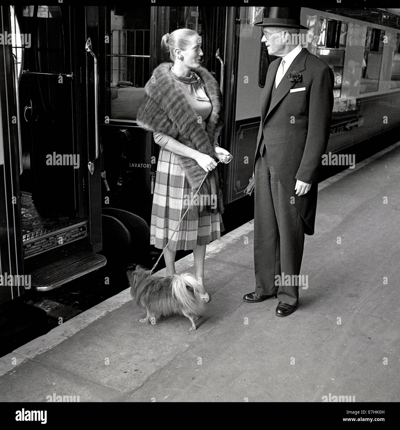 Anni Cinquanta foto storiche che mostra la stewart o maitre d' del Brighton Belle Pullman Treno Il trasporto su una piattaforma ferroviaria a Londra Victoria parlando a una smart lady passeggero con una pelliccia buttare intorno a lei e con un piccolo cane al guinzaglio. Treni Pullman iniziato nel 1874 e furono mainline lussuosi servizi ferroviari thar azionato wth di prima classe pullman e un servizio di Stewart. Foto Stock