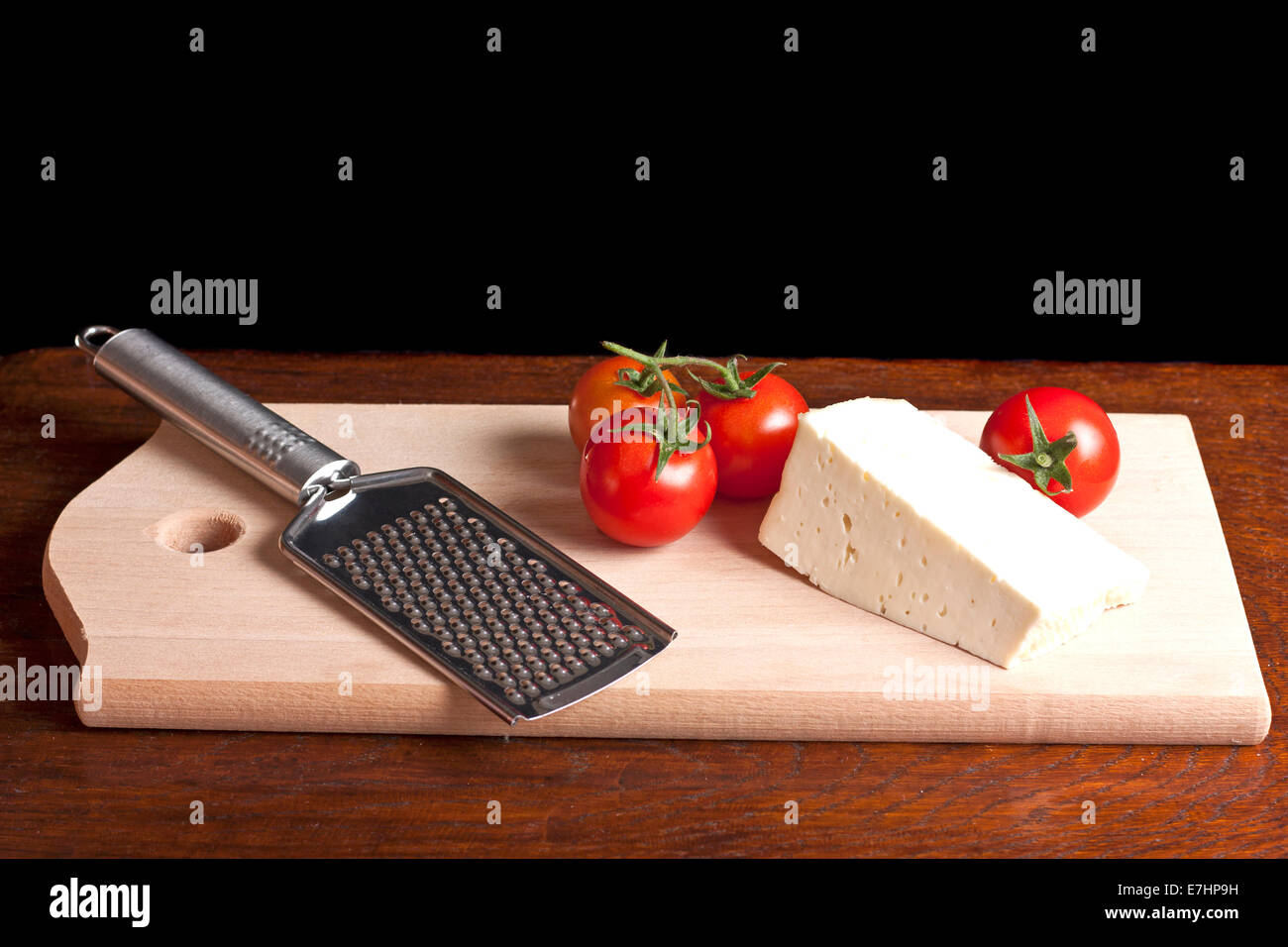 Formaggio, grattugia e rosso pomodoro su una scrivania in legno Foto Stock