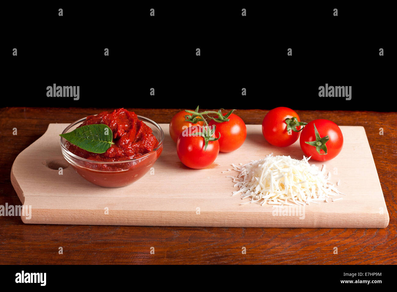 Il concentrato di pomodoro, formaggio grattugiato e alcuni pomodori su legno Foto Stock