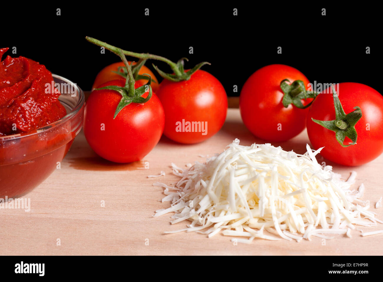 Il concentrato di pomodoro, formaggio grattugiato e alcuni pomodori su legno Foto Stock