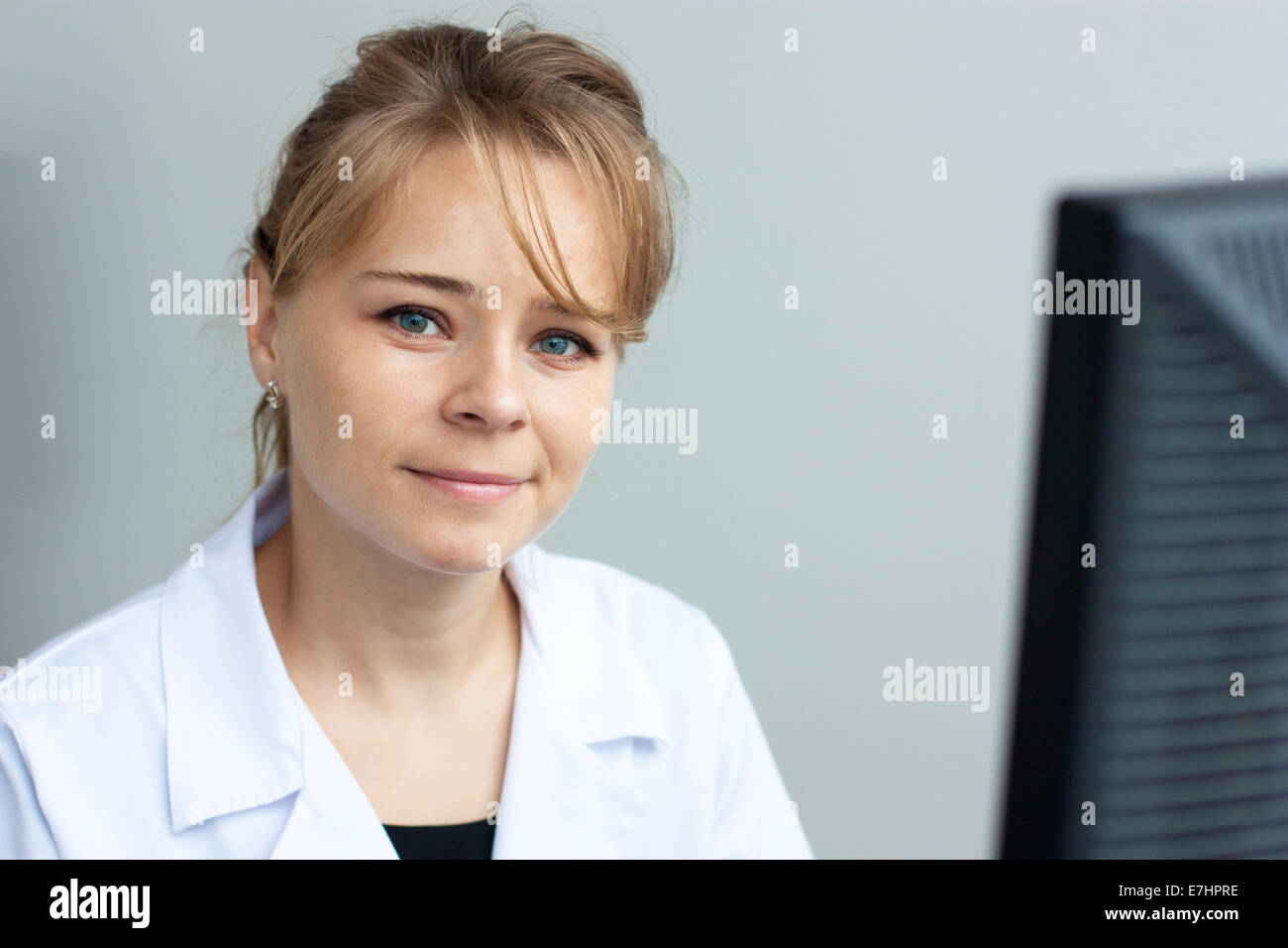 Il farmacista donna sorridente e guardando la fotocamera. Lavorare con il suo computer Foto Stock