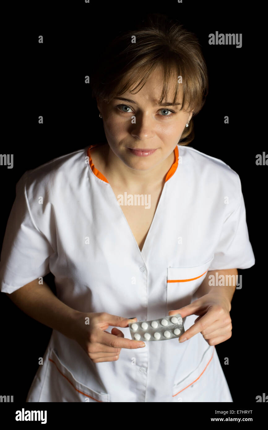 Il farmacista donna tenendo alcune pillole, isolato su nero Foto Stock