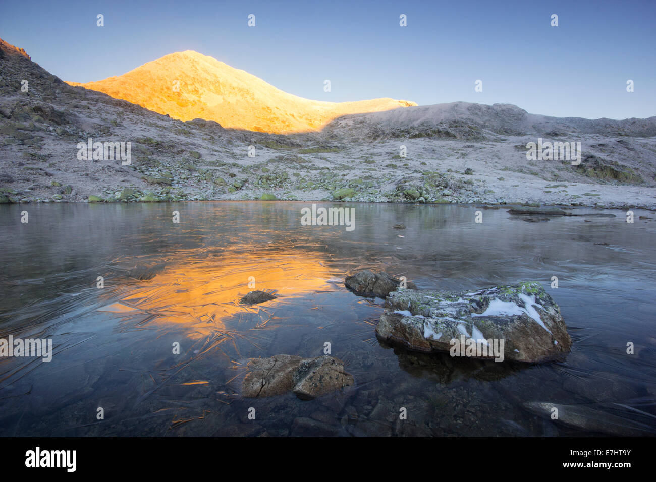 La mattina presto luce sul picco Bucura, che si riflette in un gelido lago in Retezat National Park, Carpazi Meridionali, Romania. Foto Stock