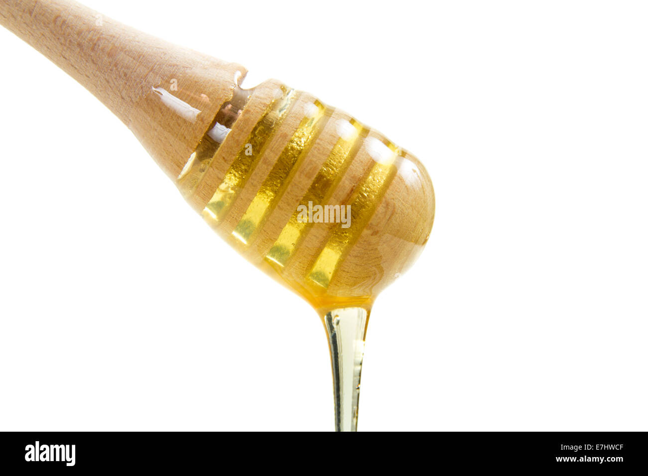 Il miele che gocciola dalla bacchetta di legno isolato su sfondo bianco Foto Stock