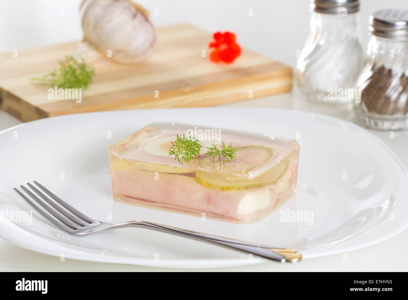 Carne in gelatina su una piastra bianca e una forcella Foto Stock