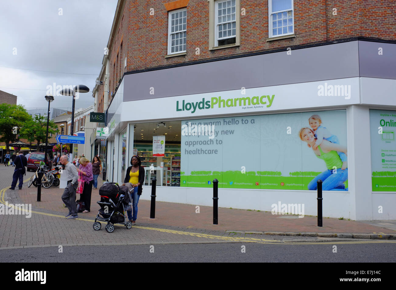 Donna con passeggino al di fuori di Lloyds farmacia in Aylesbury Foto Stock