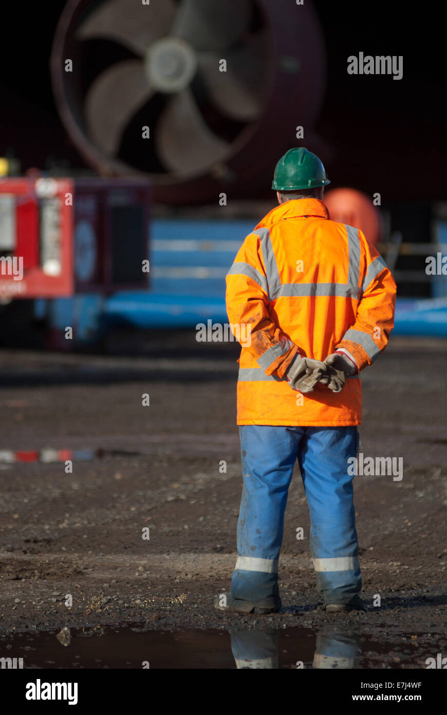 Lavoratore in cantiere indossano alta viz giacca e elmetto Foto Stock