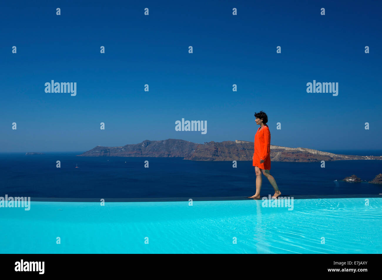 Donna che cammina lungo il bordo della piscina presso il Perivolas Hotel, Oia - Santorini, Cicladi Grecia Foto Stock