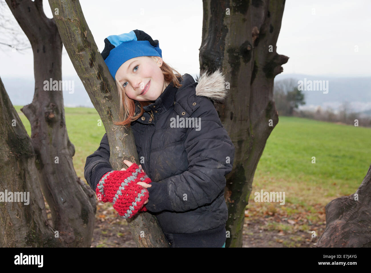 Ragazza, 9, che indossa un cappello e un paio di guanti, su una struttura ad albero Foto Stock