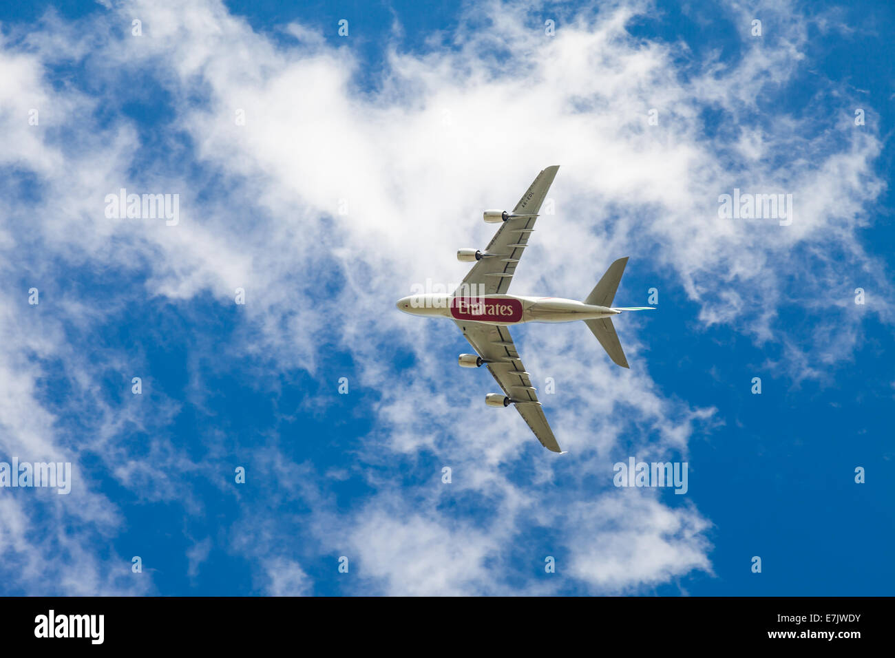 Boeing 777 Emirates A6EDL aereo Jet visto dal lato inferiore come si guadagna in altezza in un cielo blu chiaro. Logo visibile Foto Stock