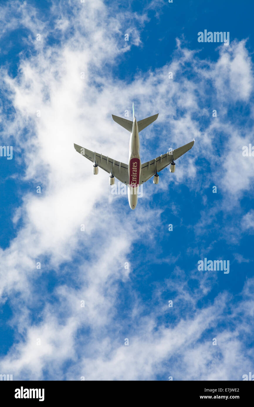 Boeing 777 Emirates A6EDL aereo Jet visto dal lato inferiore come si guadagna in altezza in un cielo blu chiaro. Logo visibile Foto Stock