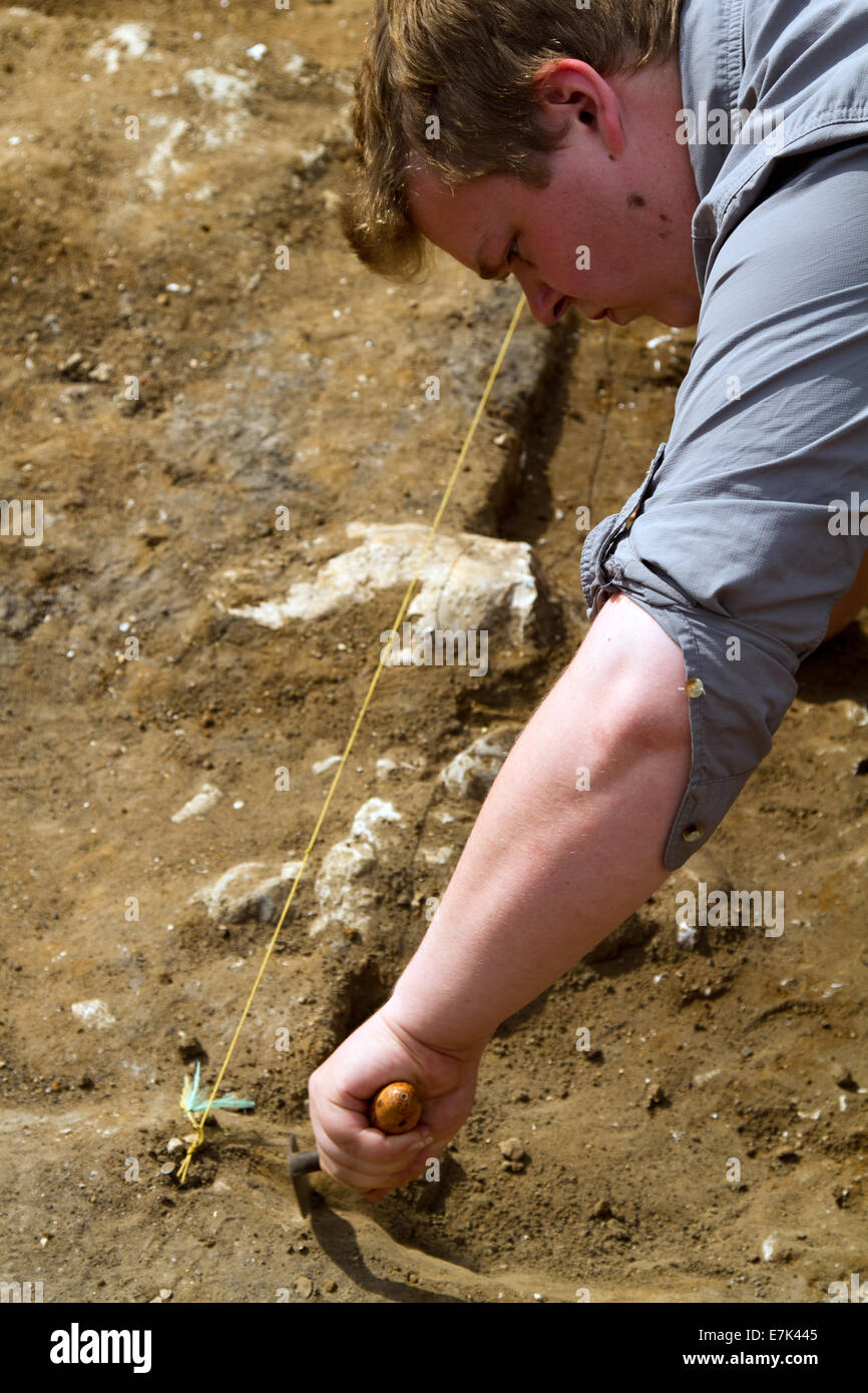 Un archeologo cancella il suolo dai resti di un antico edificio Foto Stock
