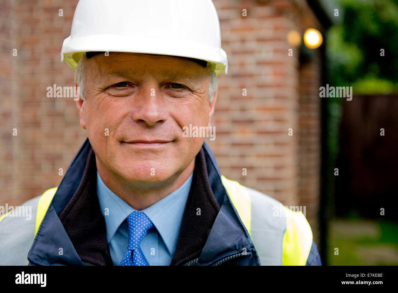 Ritratto di un sorridente imprenditore edile, indossando un bianco casco di sicurezza. Foto Stock