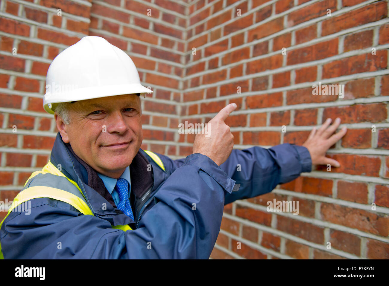 Testa e spalle vista di un tecnico di manutenzione contro un muro di mattoni in background. Foto Stock