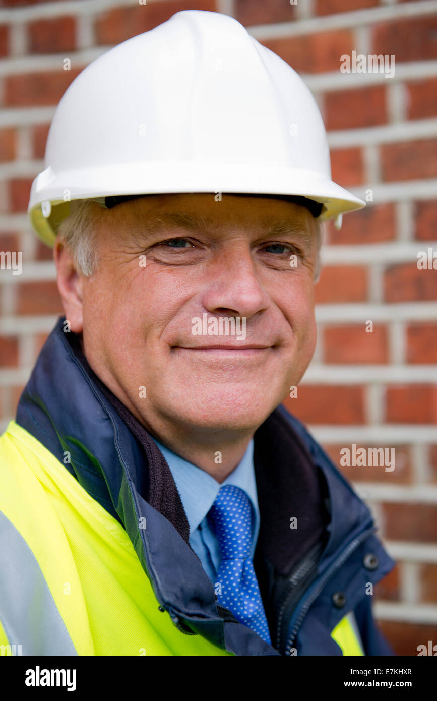 Ritratto di un sorridente imprenditore edile indossando un bianco casco di sicurezza. Foto Stock