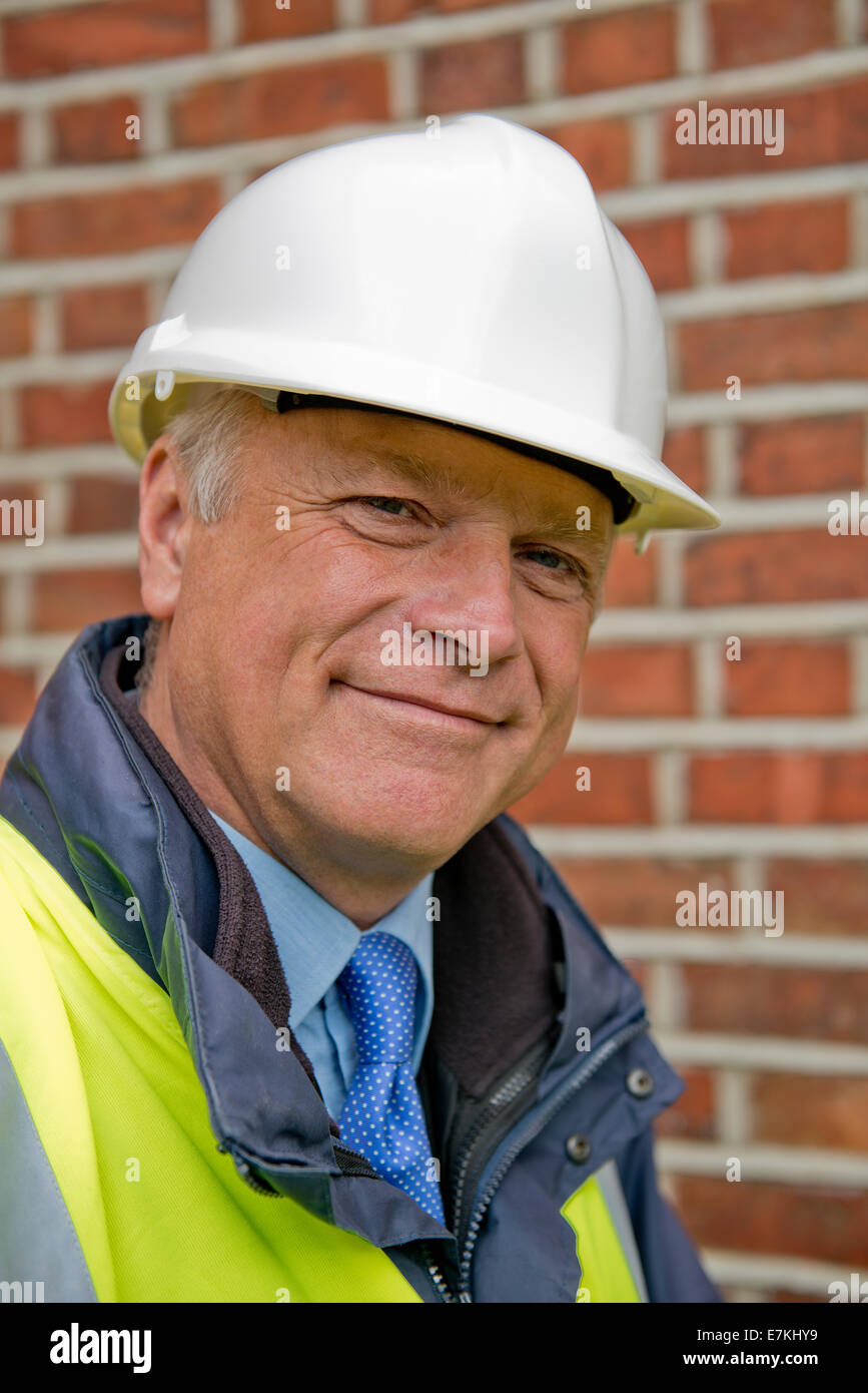 Ritratto di un sorridente imprenditore edile indossando un bianco casco di sicurezza. Foto Stock
