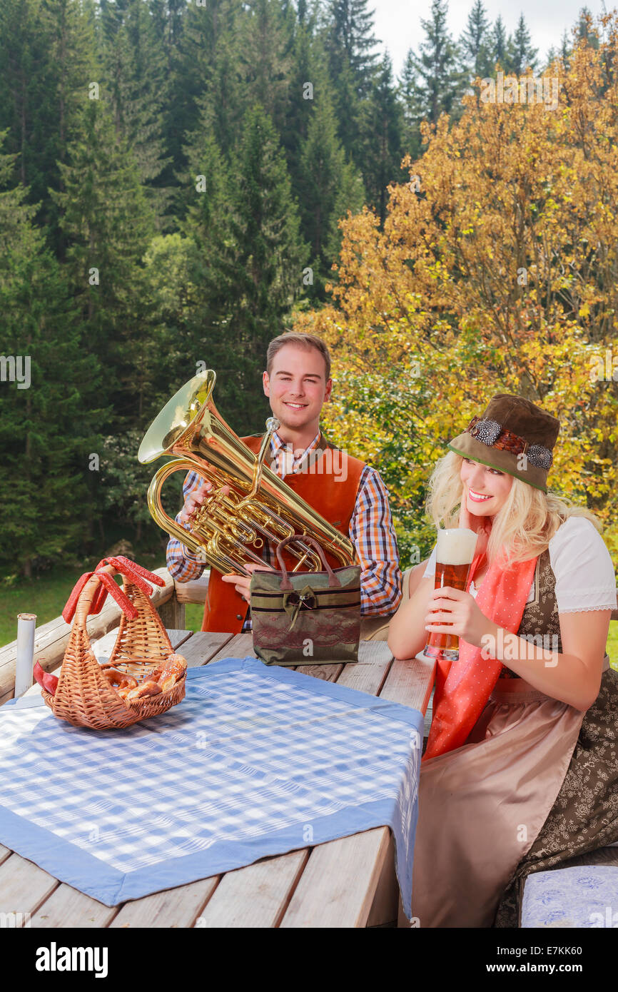 Coppia giovane in tradizionali bavaresi vestiti mentre godendo la giornata su un alpeggio in montagna Foto Stock