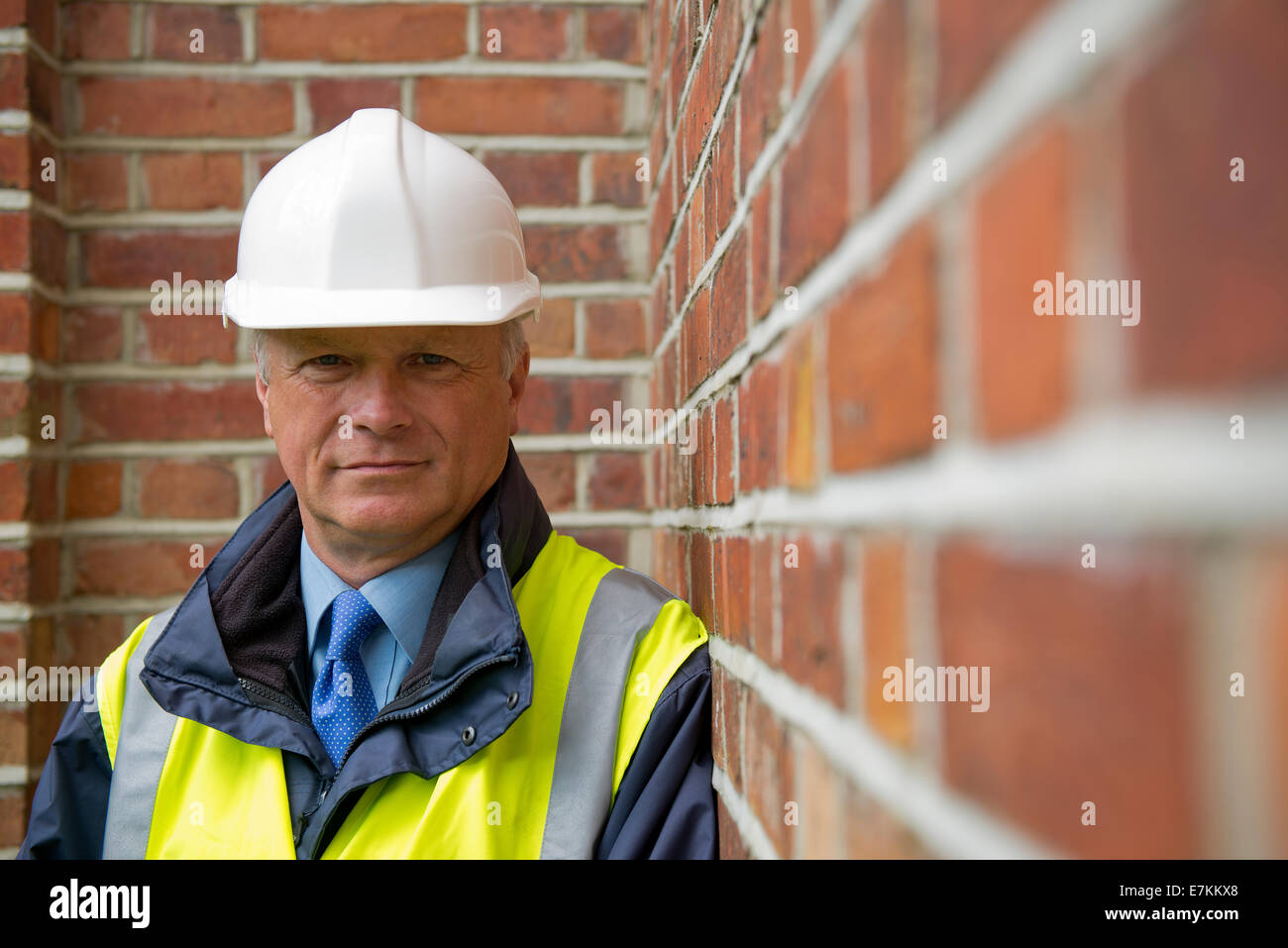 Testa e spalle vista di un tecnico di manutenzione contro un muro di mattoni in background. Foto Stock