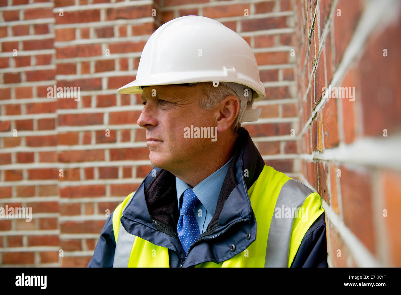 Testa e spalle ritratto di un ingegnere di costruzione contro un muro di mattoni in background. Foto Stock