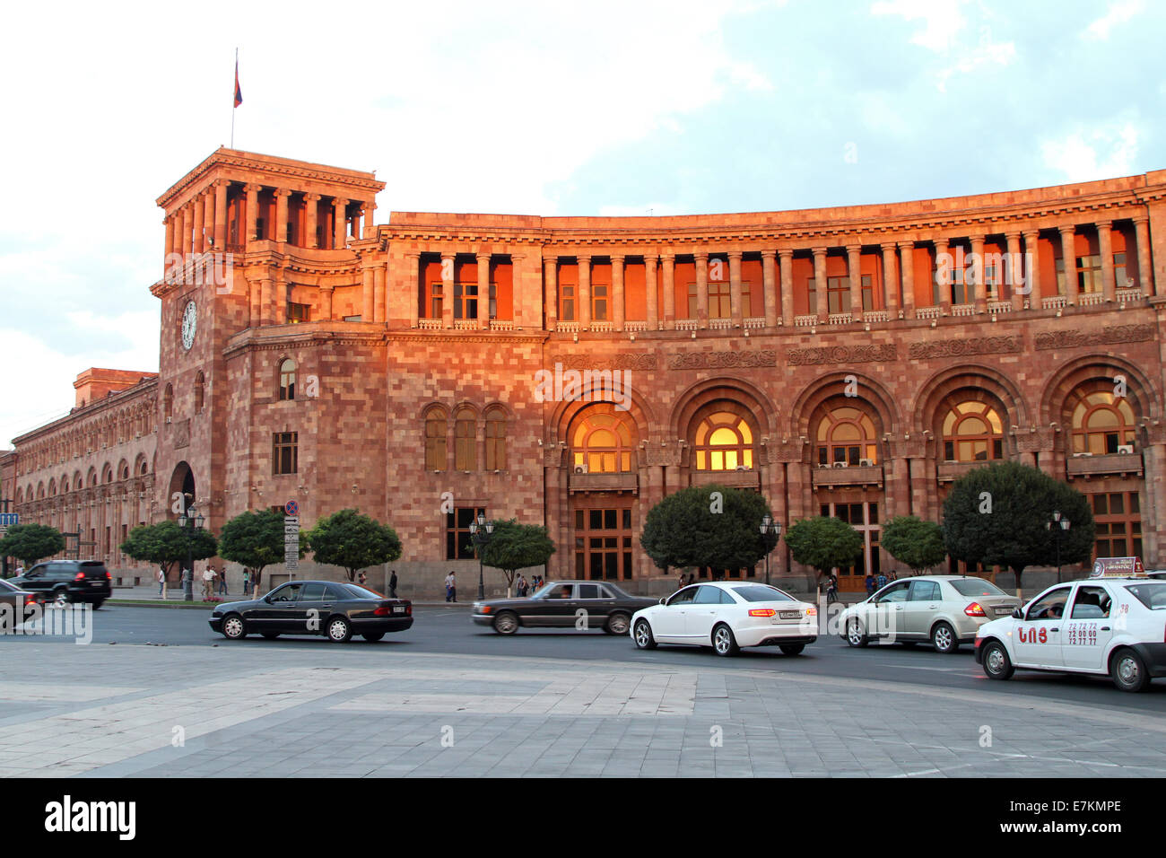 Traffico di sera fluisce oltre i principali edifici governativi in Piazza della Repubblica nel centro di Yerevan, Armenia. Foto Stock