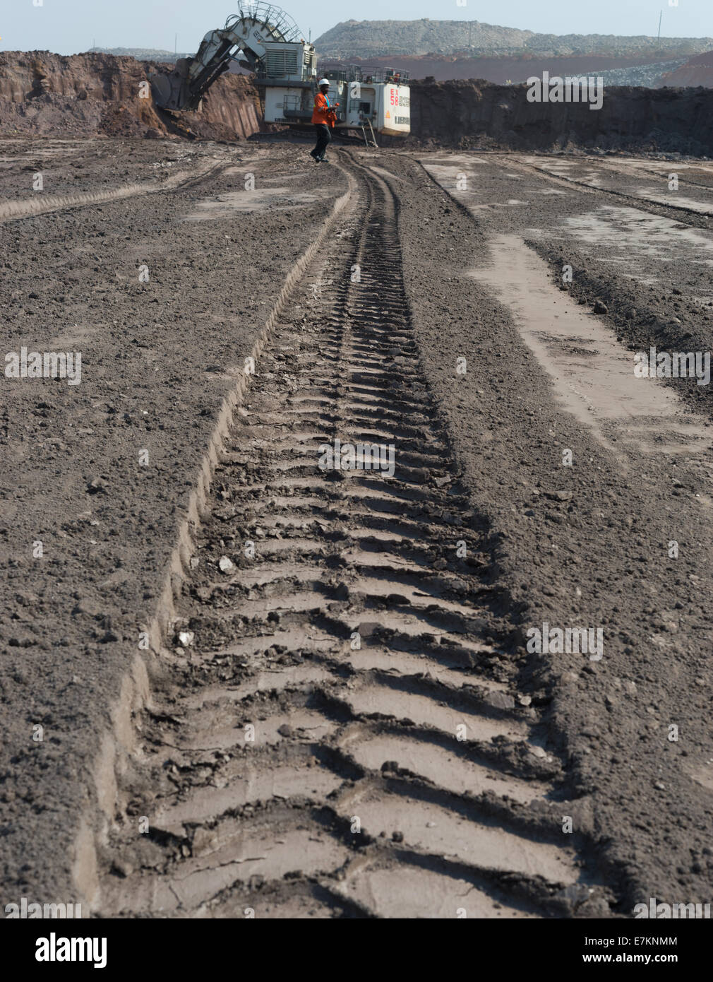 Un enorme mining carrello pneumatico indentation corre verso una massiccia Liebherr pala elettrica in attesa in distanza. Foto Stock