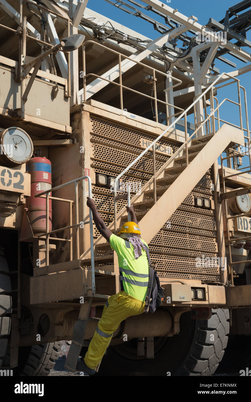 Un africano camion operatore si arrampica sulla parte anteriore della sua enorme camion all'inizio del turno in un cielo aperto miniera di rame. Foto Stock