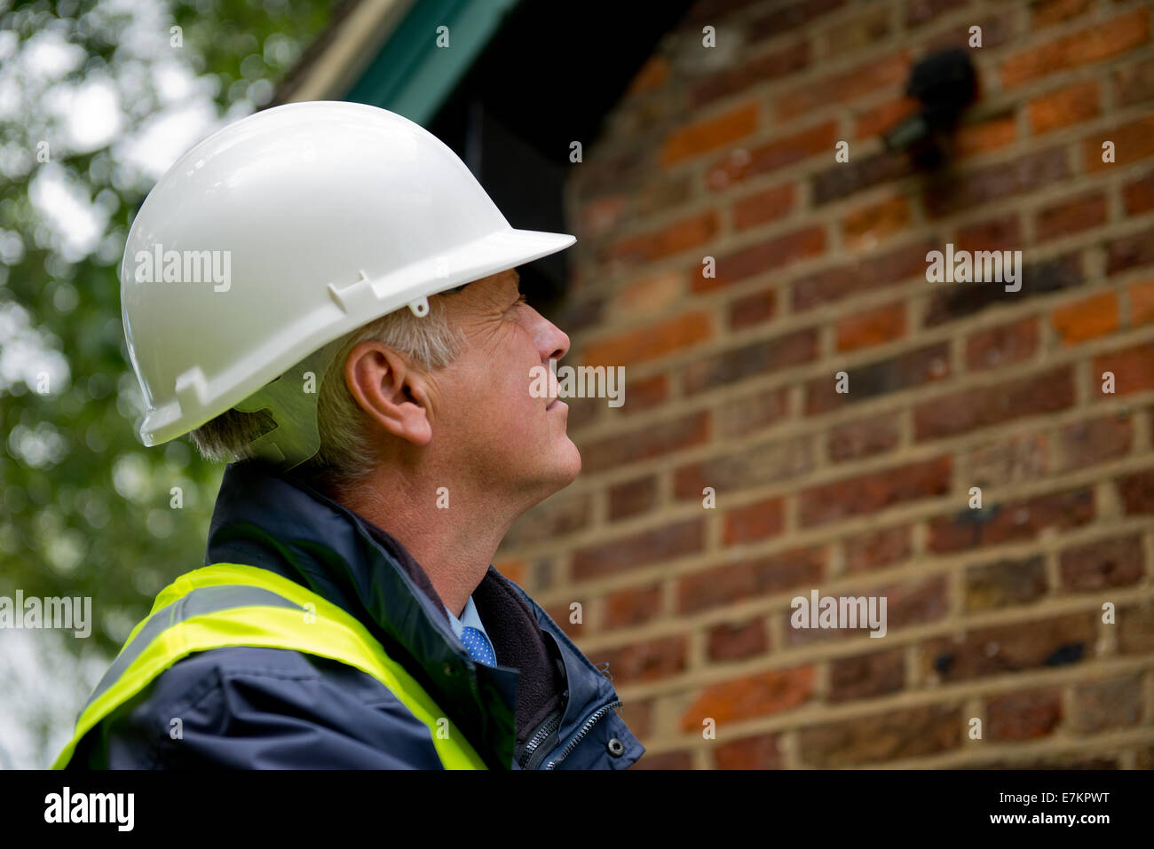 Edificio inspector, indossando un bianco casco di sicurezza, ispezionare il lato di un edificio. Foto Stock