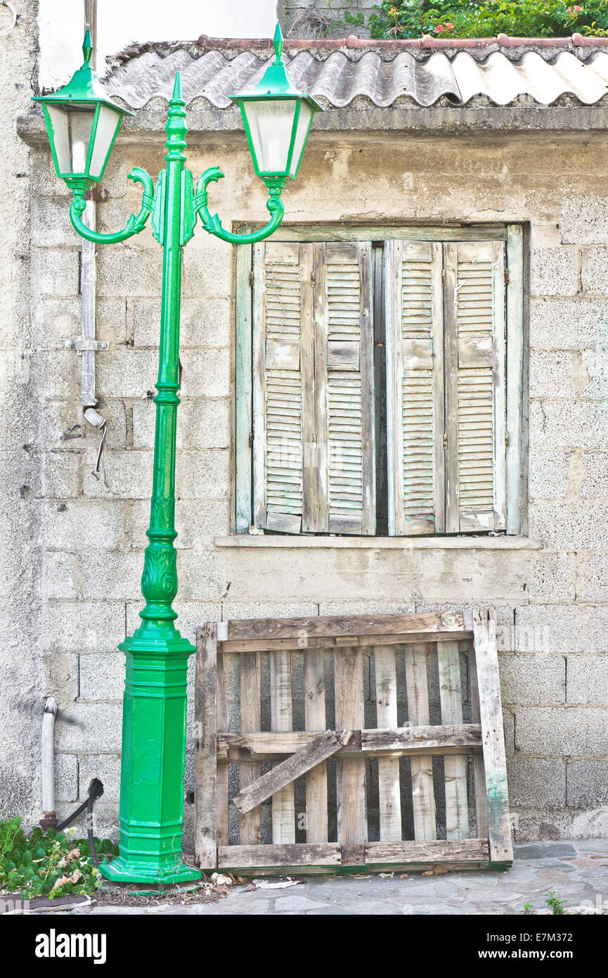 Vecchia casa in Grecia con persiane di legno e una lampada verde post Foto Stock