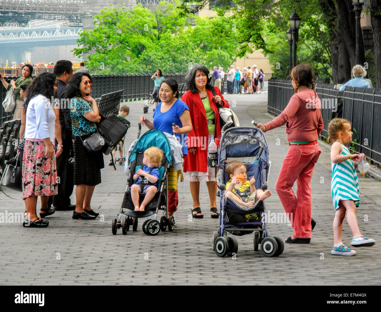 Americano asiatico bambinaie parlare con una madre nel lungomare di Brooklyn, New York. Nota i passeggini e neonati. Foto Stock