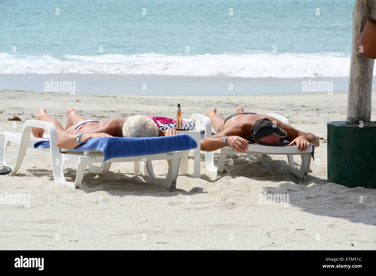 Coppia di anziani posa prendendo il sole in una spiaggia tropicale Foto Stock