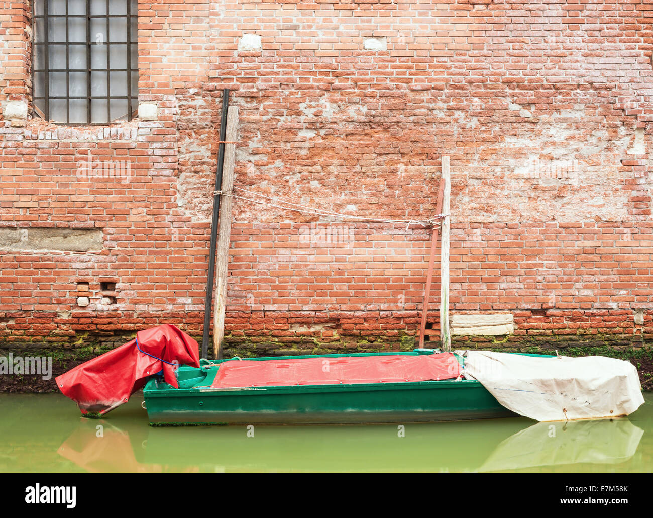 Piccola barca contro un muro di mattoni a Venezia, IItaly. Foto Stock