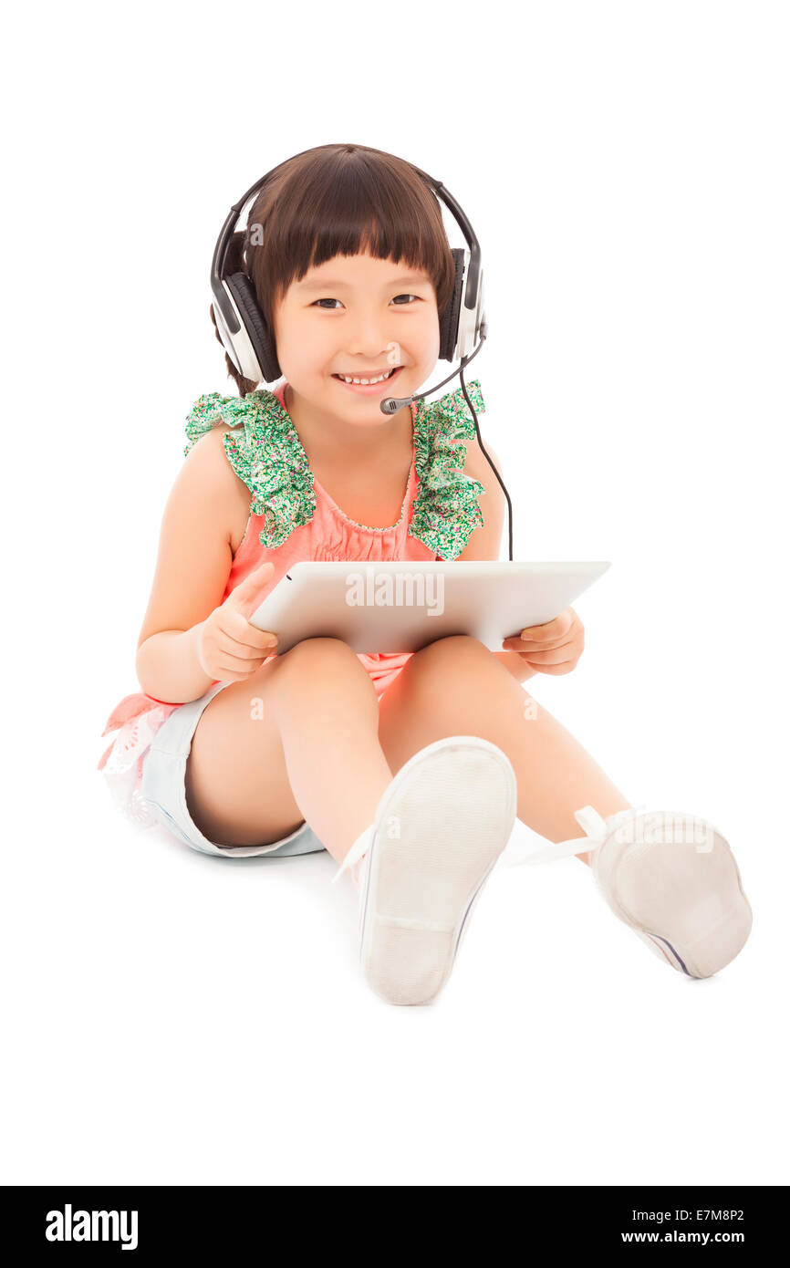 Piccolo studente ragazza seduta e tenendo un tablet con auricolare. isolato su sfondo bianco Foto Stock