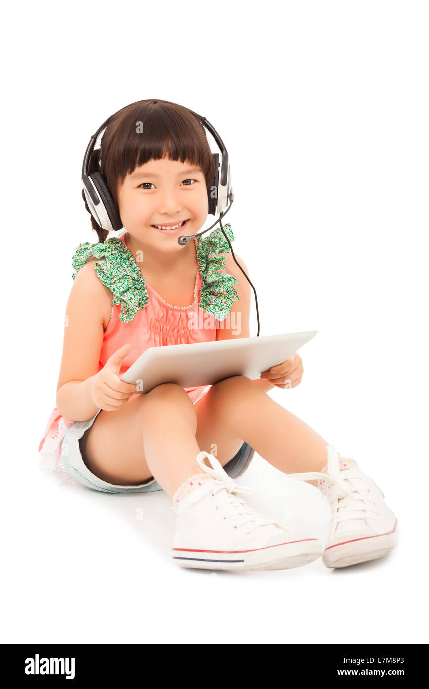 Poco sorridente ragazza studente seduto e tenendo un tablet con auricolare. isolato su sfondo bianco Foto Stock