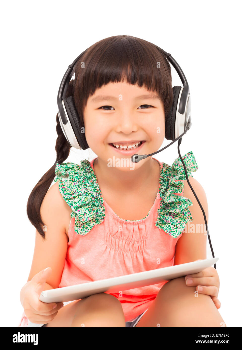 Primo piano della happys poco ragazza di studenti in possesso di un tablet con auricolare. isolato su sfondo bianco Foto Stock