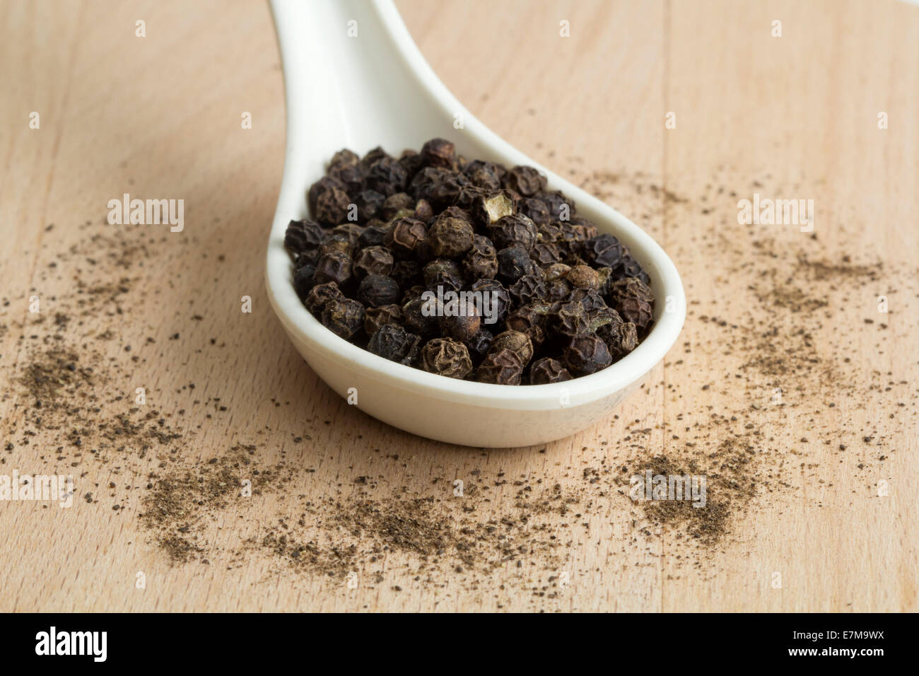 Cucchiaio colmo di peppe nero su uno sfondo di legno Foto Stock