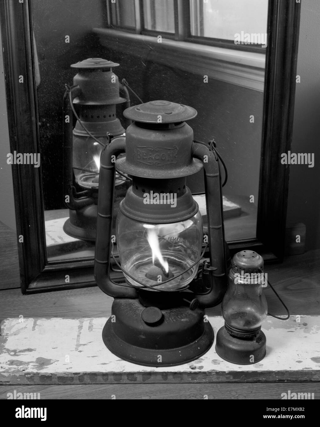 Un vecchio nero olio lampada è accesa. La fiamma brucia luminoso. Essa emerge come la riflessione dallo specchio. Piccola lanterna è accanto ad esso Foto Stock
