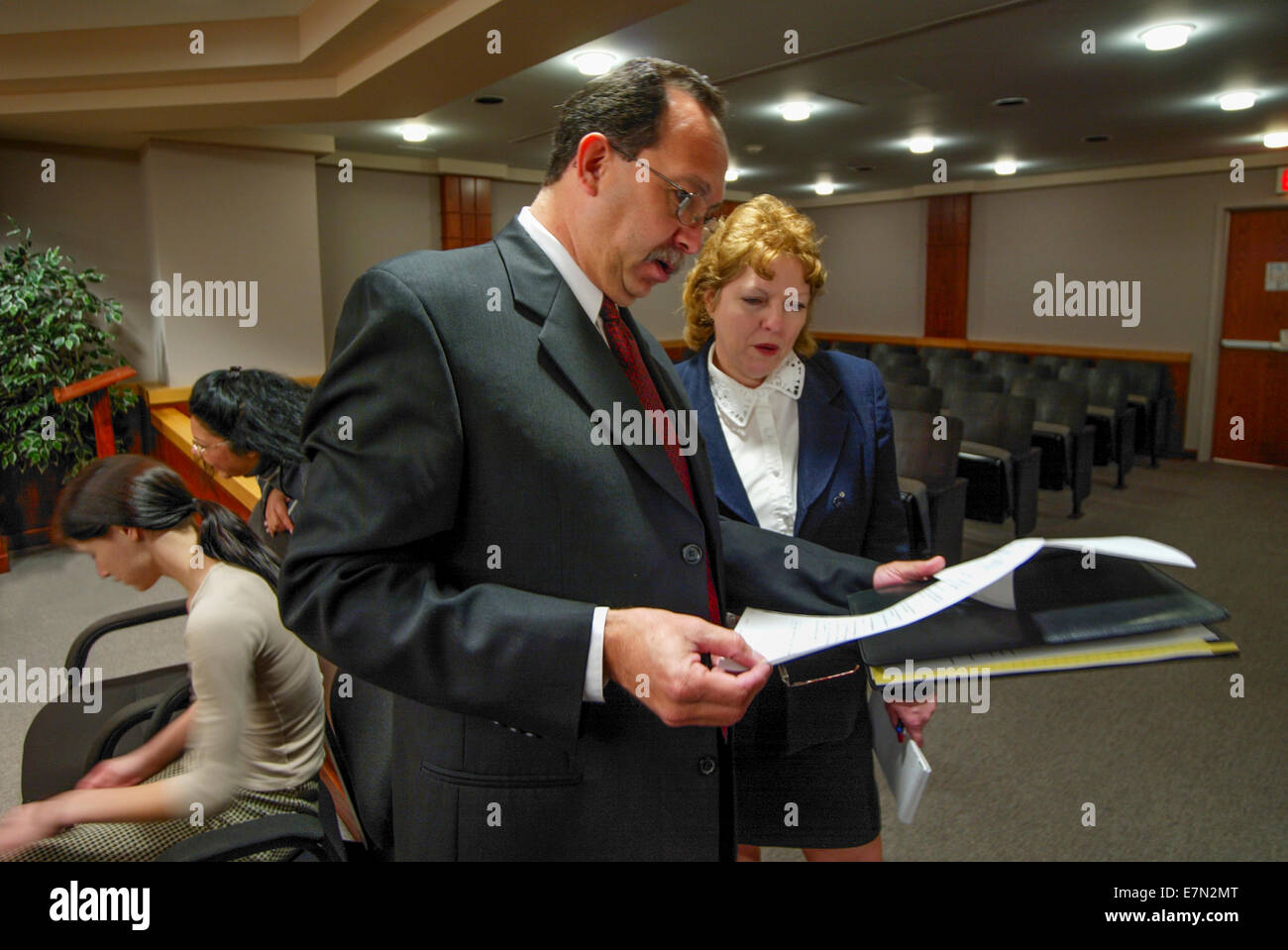 Due avvocati discutere i documenti in tribunale dei minori in arancione, CA. Nota teen ispanico convenuta a sinistra. Foto Stock