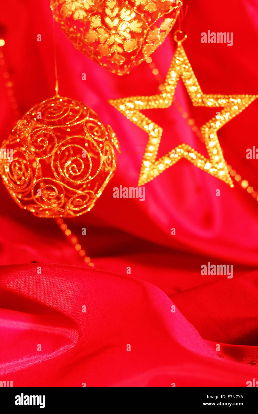 Golden decorazioni di Natale sulla stoffa rossa sullo sfondo Foto Stock