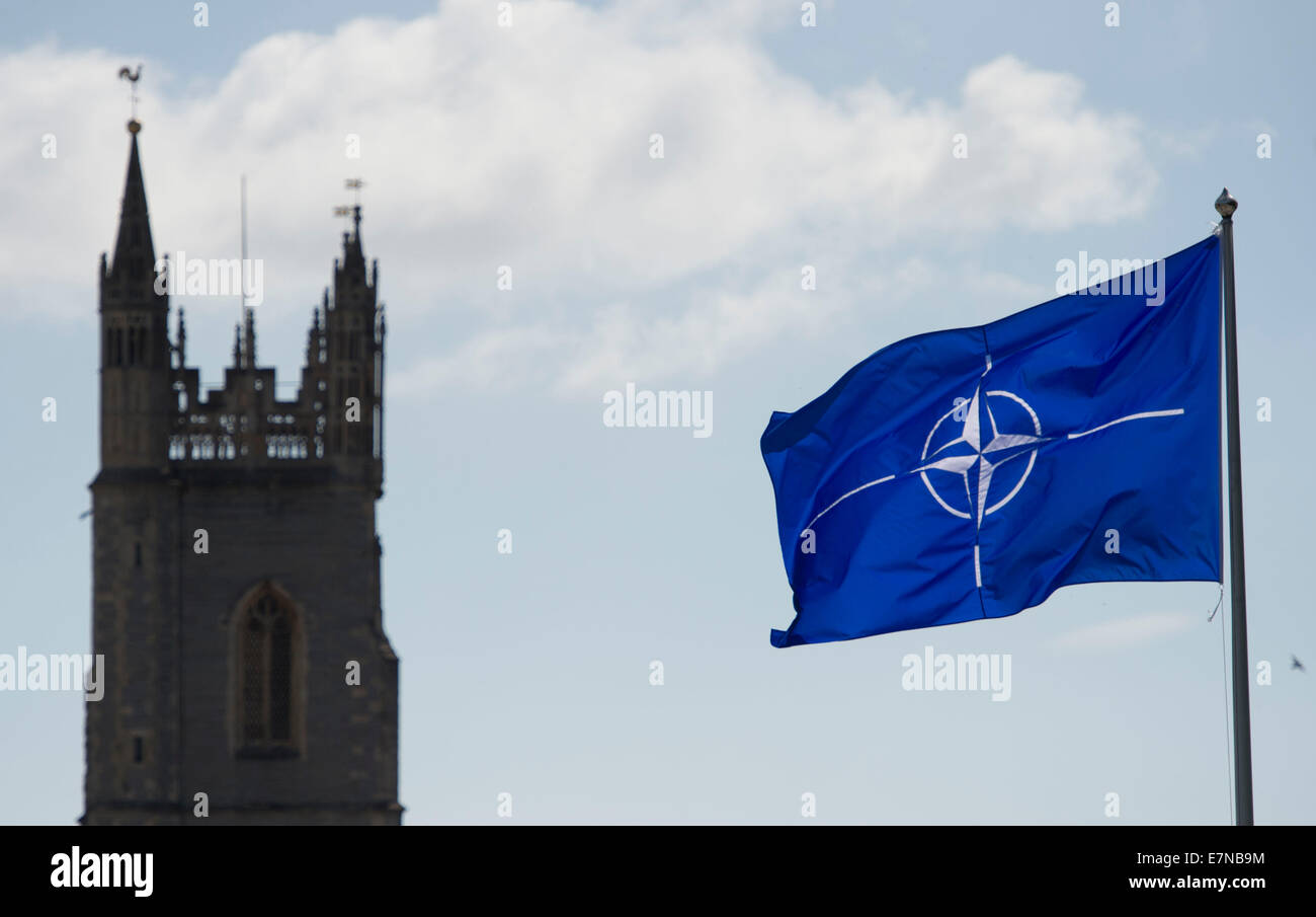 Una NATO sventola al Castello di Cardiff con la Chiesa di San Giovanni Evangelista in background dopo il vertice della NATO svoltasi a Newport. Foto Stock