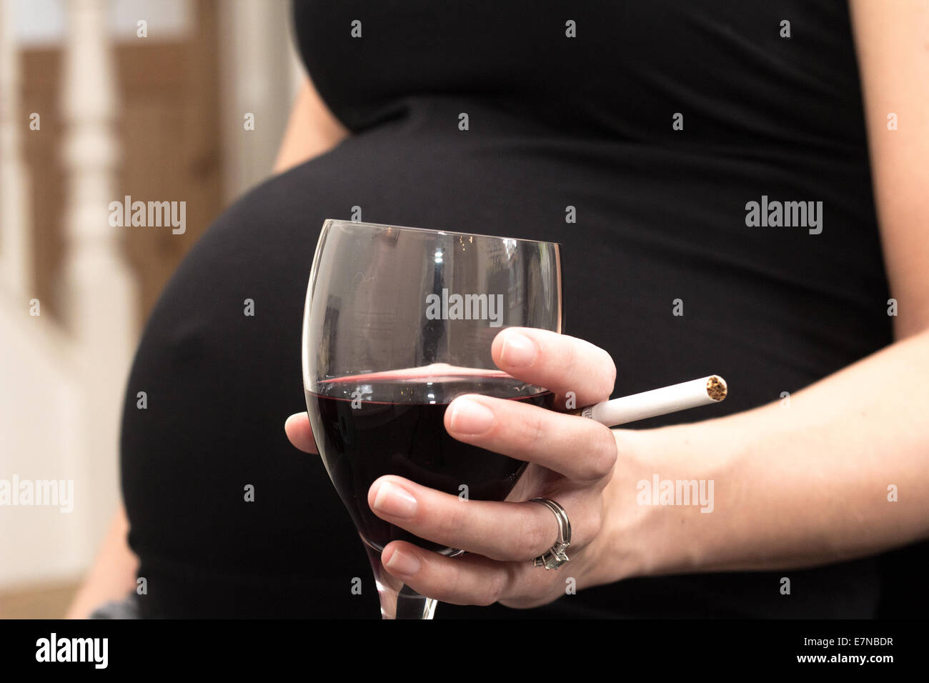 Donna incinta tenendo una sigaretta e bicchiere di vino Foto Stock