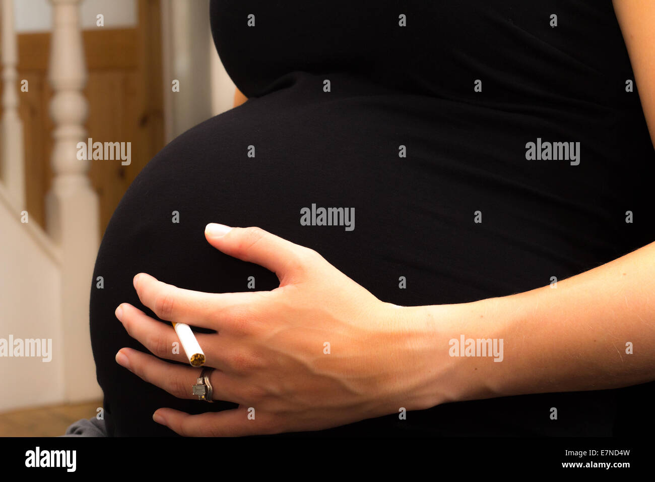 Donna incinta tenendo una sigaretta Foto Stock