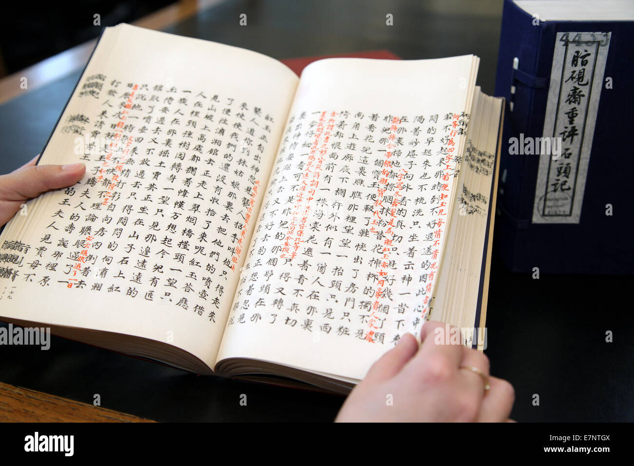 Primo piano di uno studente che studia un libro aperto di letteratura classica cinese con annotazioni rosse all'interno di una sala di ricerca della biblioteca universitaria. Foto Stock
