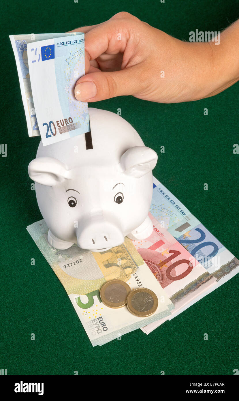 Di euro e un salvadanaio salvadanaio con una ventina di banconote in euro  che viene inserito nella scanalatura Foto stock - Alamy