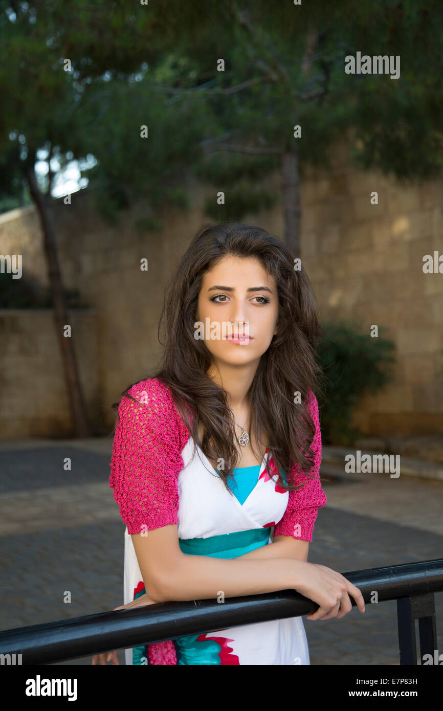 Considerato giovane donna appoggiata contro la ringhiera cercando di distanza all'aperto Foto Stock