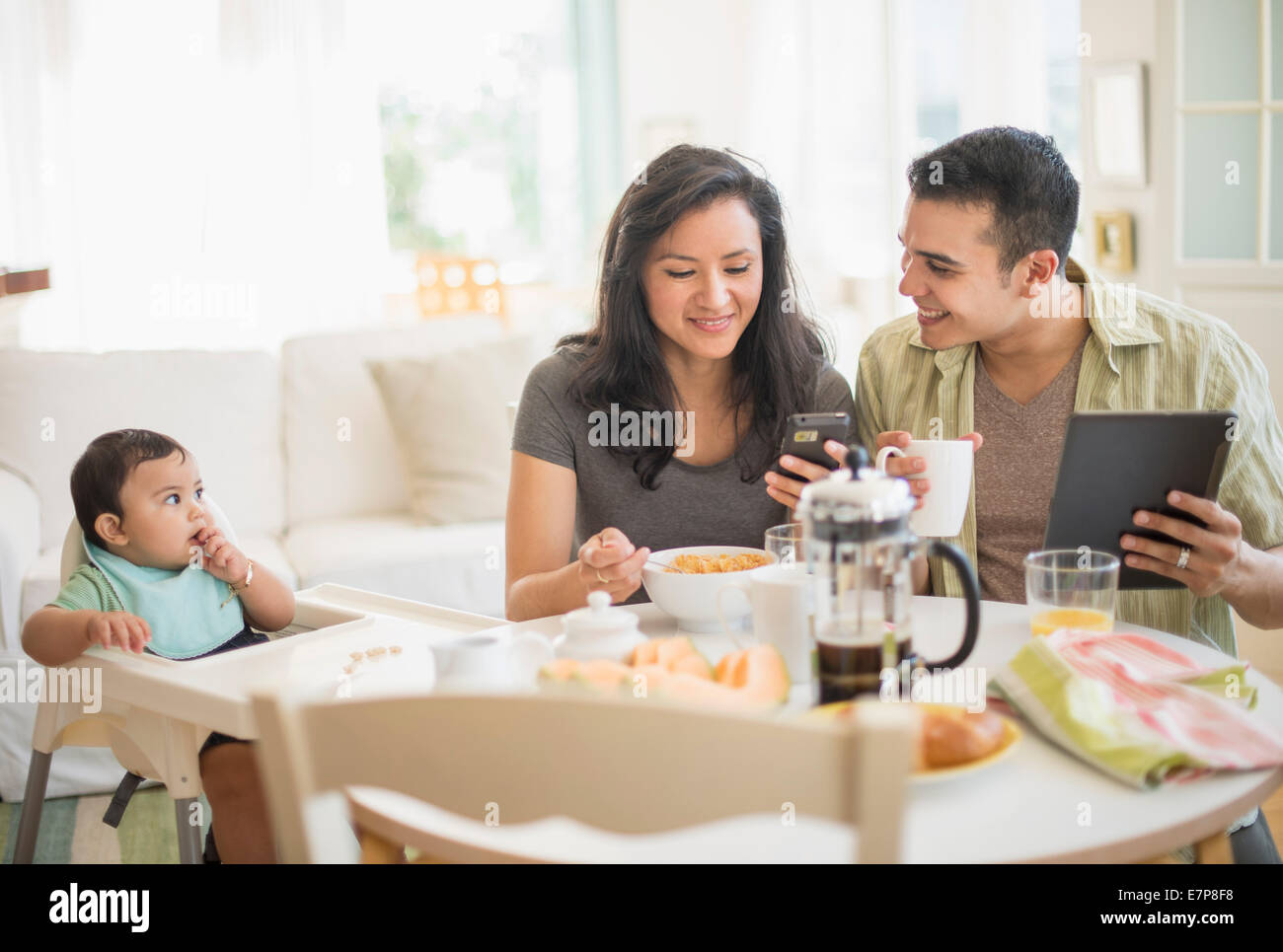 Famiglia con bambino figlio (6-11 mesi) in sala da pranzo Foto Stock