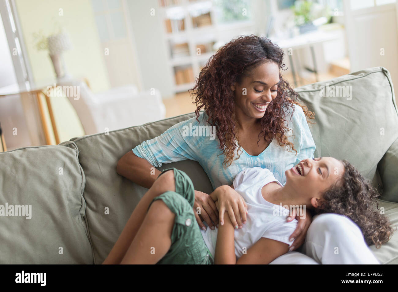 Madre figlia solletico (8-9) sul divano Foto Stock