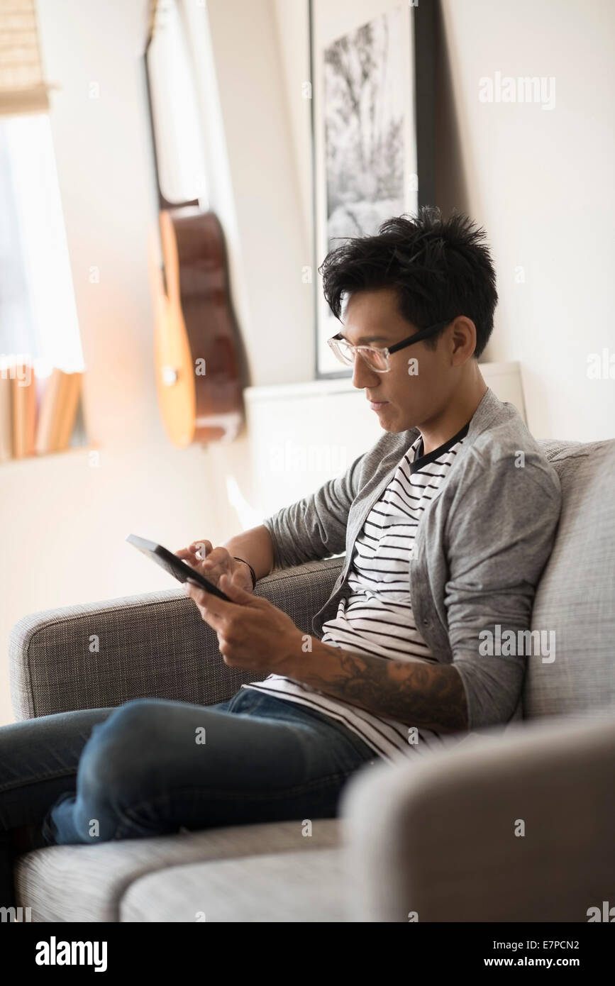 Uomo seduto sul divano e utilizzo di tablet Foto Stock